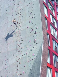 a man climbing up the side of a tall building next to a red and white building