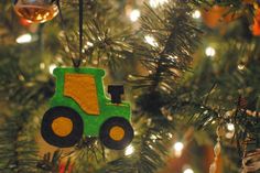 a christmas ornament hanging from a tree with lights in the background and a tractor on it