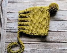 a yellow knitted hat sitting on top of a wooden floor next to a string