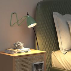 a nightstand with a lamp on top of it next to a green headboard and bed