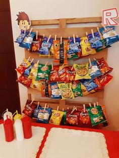 a table topped with lots of candy bags on top of a wooden rack next to a cake