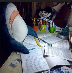 a stuffed animal is sitting at a desk with books and pencils in front of it