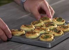 a person is placing mini pizzas on a tray