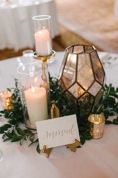 a table topped with candles and greenery next to a sign that says reserved on it