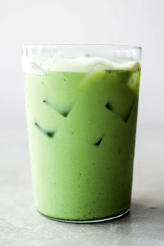 a glass filled with green liquid on top of a table