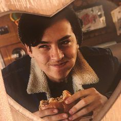 a woman holding a piece of food in front of her heart - shaped photo frame