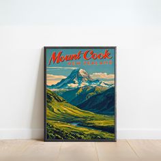 a vintage poster advertising mount cook new zealand on the wall in a room with hardwood flooring