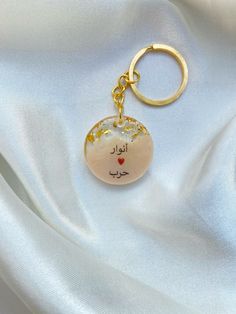 a keychain with an arabic writing on it sitting on a white satin background