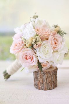 a bouquet of pink and white flowers sitting on top of a tree stump