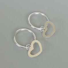 A PAIR of sterling silver hoops. Comes with a detachable heart charm. The charm is multipurpose and can be used with a neck or bracelet chain too. Dimension: Hoop- 14 x 1.5 mm Heart: 11 x 11 mm Price listed is for a PAIR of hoops. These earrings are made of 925 hypoallergenic sterling silver and comes with a 925 stamp. Can be packaged in a gift box. I can include a personal message from you if needed You are welcome to contact me at... bhavnakwintra1956@gmail.com For more beautiful pieces from m Dainty Sterling Silver Hoop Earrings With Heart Charm, Cute Sterling Silver Hoop Earrings, Silver Heart Hoop Earrings For Gift, Small Hoop Earrings With Heart Charm, Minimalist Sterling Silver Hoop Earrings With Heart Charm, Silver Sterling Heart Charm Huggie Earrings, Gift Sterling Silver Small Hoop Heart Earrings, Sterling Silver Small Hoop Heart Earrings For Gift, Silver Hoop Earrings With Heart Charm