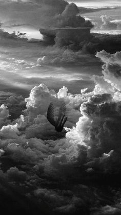 a black and white photo of a hot air balloon flying in the sky with clouds