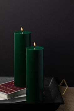 two green candles sitting on top of a tray