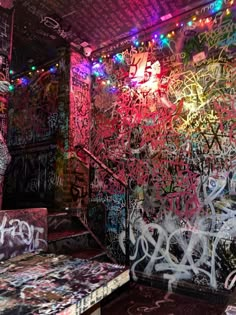 graffiti covered walls and benches in a room with lights on the ceiling, and stairs leading up to them