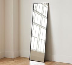 a tall mirror sitting on top of a wooden floor