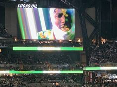 a large screen in the middle of a stadium with lights on it's sides