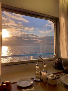 the sun is setting over the ocean as seen from a dining room on a boat