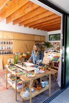 a woman standing in front of a table filled with art supplies