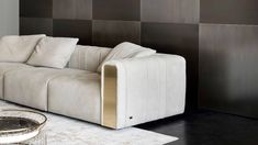 a white couch sitting in front of a wall with black and gold panels on it