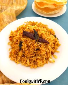 a white plate topped with rice next to another plate filled with food on top of a blue table