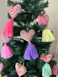 a small christmas tree decorated with multicolored hearts and tassels on it