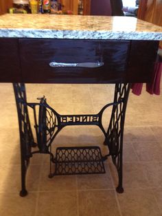 an old sewing machine is sitting on the floor in front of a table with drawers