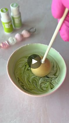 a person holding a spoon in a bowl filled with green liquid next to other items