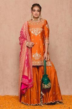 Orange silk kurta in floral embroidered gota work. Paired with banarsi bandhani dupatta and sharara.
Component: 3
Pattern: Embroidered
Type Of Work: Gota work
Neckline: Round
Sleeve Type: Three quarter
Fabric: Cotton, Silk, Georgette
Lining: Cotton
Color: Orange
Other Details: 
Scallop sharara
Georgette embroidered dupatta
Note: Potli held by the model is not for sale
Note: Green kurta lehenga set worn by the other model is not for sale
Occasion: Sangeet - Aza Fashions Banarsi Suit Design Indian Style, Orange Sharara, Sharara Suit Designs, Lehenga Ideas, Stitching Styles, Kurta Lehenga, Bandhani Dupatta, Mehndi Outfits, Kurta Sharara Set