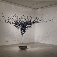 a black bowl sitting on top of a cement floor in front of a white wall