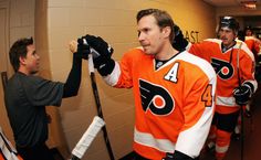 an ice hockey player is talking to his coach in the locker room with other players