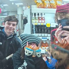 two young men are taking pictures with their cell phones in front of a store window