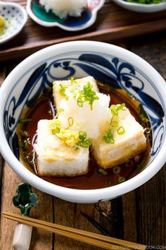 some food in a bowl with chopsticks on the side