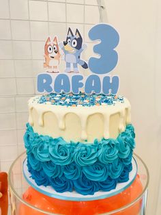 a three tiered cake with blue and orange frosting on it's side