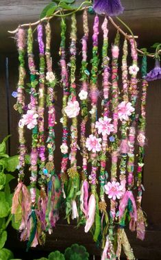 a close up of a wind chime hanging from a wooden fence with flowers and leaves