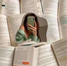 a woman taking a selfie in front of an open book with her cell phone