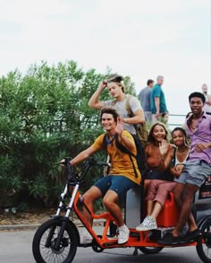 a group of young people riding on the back of a small motorcycle with two passengers