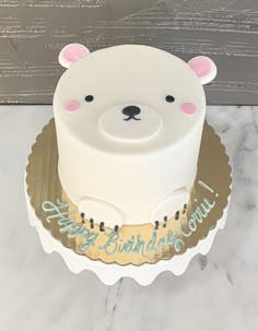 a birthday cake decorated with a white polar bear head and gold trimmings on a marble table