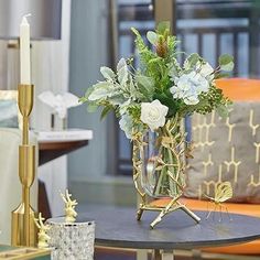 a glass vase filled with flowers sitting on top of a table next to a candle