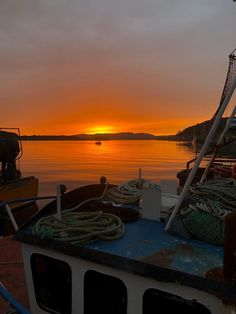 the sun is setting over some boats in the water with ropes on top of them