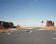 a red stop sign sitting on the side of a road next to tall rocks in the desert