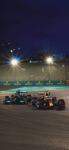 two racing cars driving down the track at night