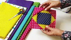 a person is cutting fabric with scissors on a table next to some crafting supplies