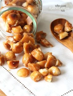 some nuts are in a glass jar on a white towel next to a wooden spoon