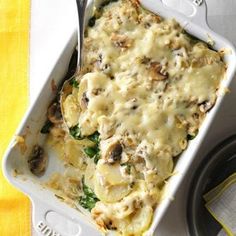 a casserole dish with cheese and spinach in it next to a fork