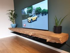 a flat screen tv sitting on top of a wooden shelf next to a potted plant