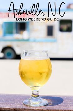 a glass of beer sitting on top of a wooden table next to a food truck