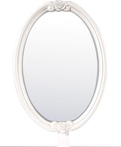 an oval white mirror sitting on top of a table