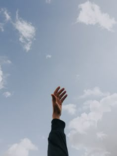 a person reaching up into the sky to catch a frisbee with their hands