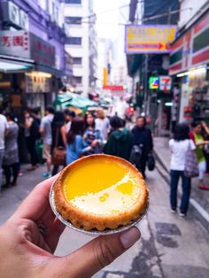 a person holding up a pastry in the middle of a crowded street