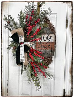 a wreath with red berries and greenery hangs on a door