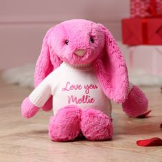 a pink stuffed rabbit with love you mollie on it's chest sitting on the floor